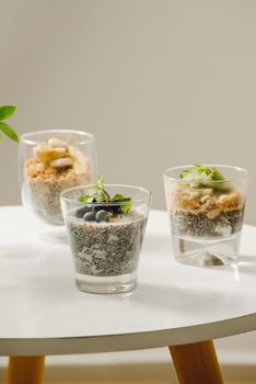 Fruits yogurt parfait with granola and chia seeds for healthy breakfast on wooden table