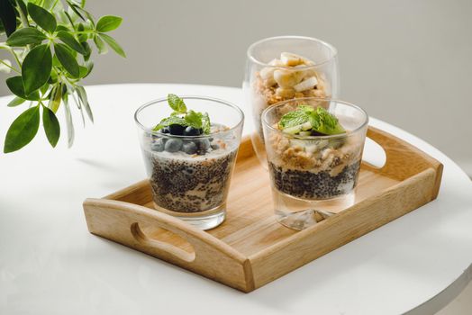 Fruits yogurt parfait with granola and chia seeds for healthy breakfast on wooden table