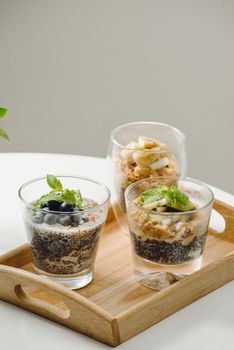 Fruits yogurt parfait with granola and chia seeds for healthy breakfast on wooden table