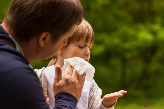 The father takes care of his little son. The father wiped the child's face with a napkin. Baby care, paternity, custody.