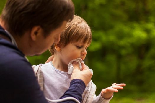 The father takes care of his little son. The father wiped the child's face with a napkin. Baby care, paternity, custody.