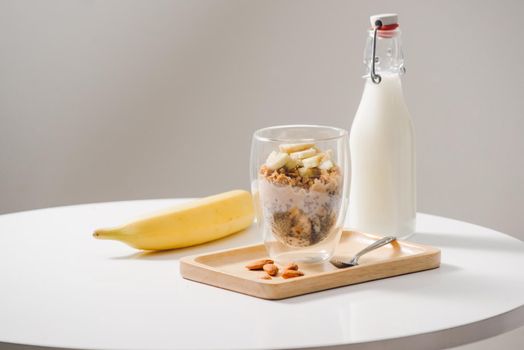 Ready to eat healthy an nutritious breakfast - granola with almonds, chia seeds, banana and kiwi fruits and berries and a jar with milk nearby