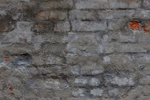 old brick wall with shabby gray cement plaster layer - background and texture