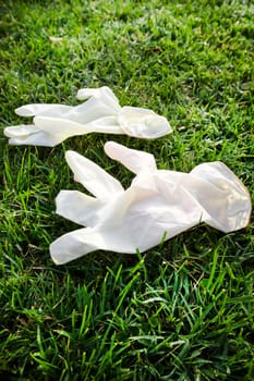 Photographic representation of a pair of disposable anti Coronavirus gloves thrown into the ground causing pollution. 