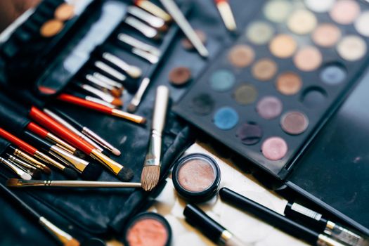 Makeup artist set. A palette of eyeshadows in different colors and a set of makeup brushes with blush in a black cosmetic bag. High quality photo