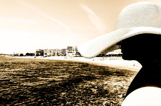 Woman in big white on Cap Negret beach on a sunny day of Spring in Altea, Alicante, Spain