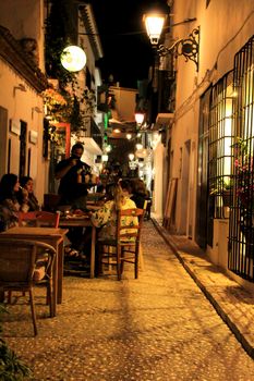 Altea, Alicante, Spain- June 12, 2021: People having drinks and enjoying nice weather in terraces at night in Altea village in Spain. 