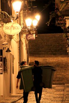 Altea, Alicante, Spain- June 12, 2021: Waitress of a restaurant taking the garbage out in Altea village, Alicante, Spain