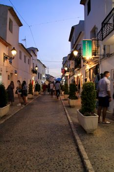 Altea, Alicante, Spain- June 12, 2021: People going shopping, walking and relaxing at night through the Narrow streets of Altea village, Alicante, Spain