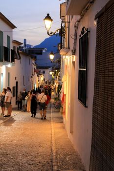 Altea, Alicante, Spain- June 12, 2021: People going shopping, walking and relaxing at night through the Narrow streets of Altea village, Alicante, Spain