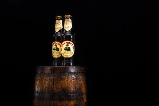 Bottle of Birra Moretti beer on wooden barrel with dark background. Illustrative editorial photo Bucharest, Romania, 2021