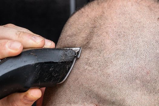 Man shaving or trimming his hair using a hair clipper