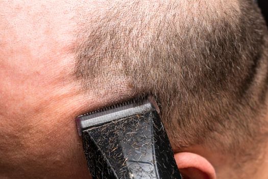 Man shaving or trimming his hair using a hair clipper