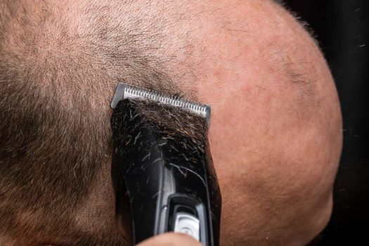 Man shaving or trimming his hair using a hair clipper