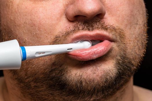 Close up of man brushing his teeth with electric toothbrush