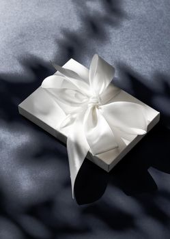 Anniversary celebration, shop sale promotion and luxe surprise concept - Luxury holiday white gift box with silk ribbon and bow on black background, luxe wedding or birthday present