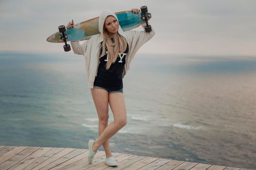 Beautiful and fashion young woman posing with a skateboard