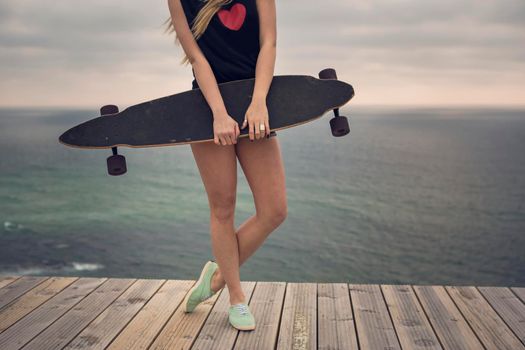 Beautiful and fashion young woman posing with a skateboard