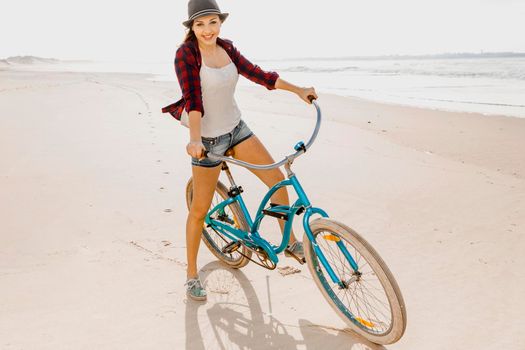 An attractive young woman riding her bicycle on the beach