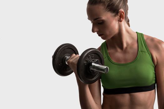 Beautiful young woman in a workout gear lifting dumbbells