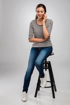 Beautiful happy young woman sitting on a bench making a phone call