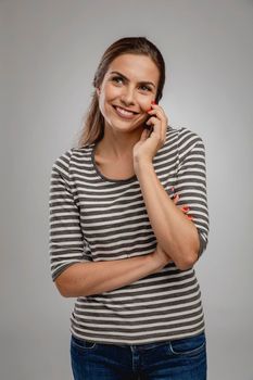 Portrait of beautiful happy young woman over a gray background making a phone call