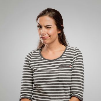 Portrait of a beautiful happy winking, over a gray background