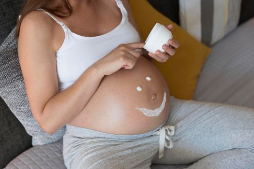 Pregnant woman applying stretch mark cream in her belly