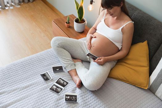 Pregnant woman looking to the picture of the ultrasound, Prenatal health care concept.