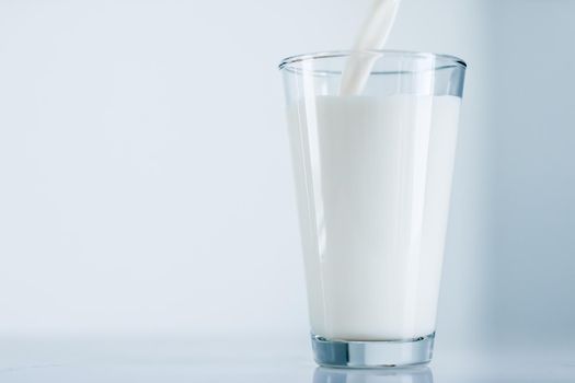 Dairy, healthy nutrition and breakfast concept - World Milk Day, pouring into glass on marble table