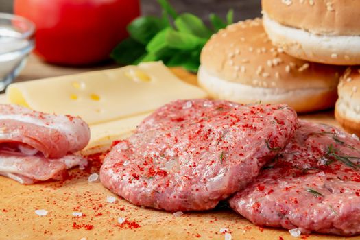 Process of cooking homemade burgers, meatballs, tomatoes, cheese and other ingredients on a wooden background, close up.