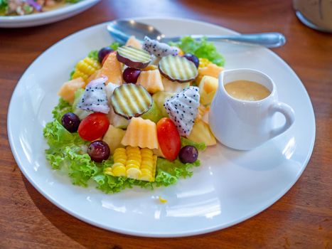 Vegetable salad on a white plate placed on a wooden background.