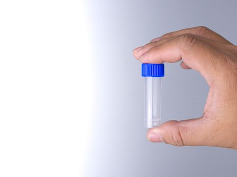 human hand holding a vaccine bottle with two fingers.