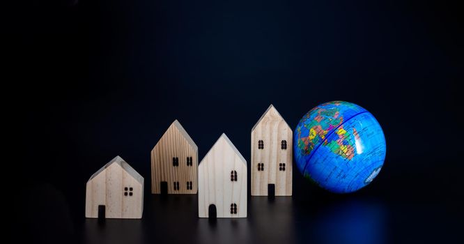 Model wooden houses and miniature globes Blank on a black background. Propose the concept of coexistence in the same world.