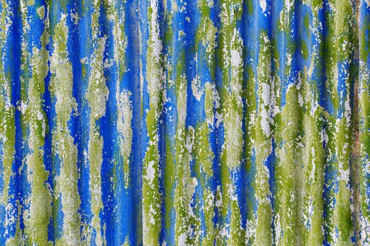 colorful motley peeled off paint layers on corrugated zinc coated steel sheet - full frame background and texture