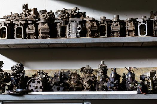 old dirty metal engine parts on dark garage shelf.