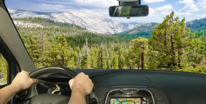 Driving a car in towards a beautiful green valley inside Yosemite National Park, California, USA