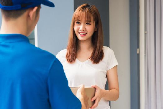 Asian young delivery man courier in uniform hold parcel post boxes service shipment woman customer receiving accepting parcel from delivery at front home, Online shopping service concepts