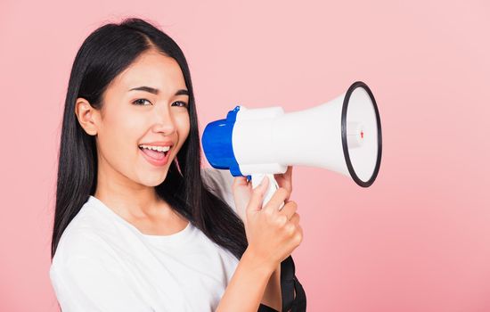 Portrait of happy Asian beautiful young woman teen confident smiling face holding making announcement message shouting screaming in megaphone, studio shot isolated on pink background, with copy space