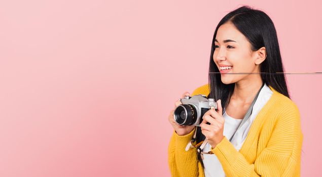 Attractive happy Asian portrait lifestyle beautiful young woman excited smiling photographer holding retro vintage photo camera ready to shoot isolated on pink background, tourism and vacation concept
