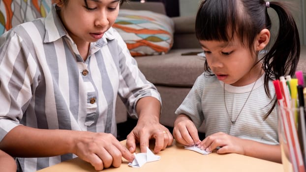 Mother and children learning about The Japanese art of folding paper into decorative shapes and figures at home.