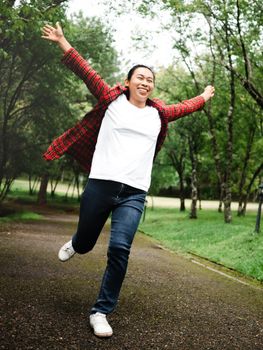 A happy female tourist looking up at the sky with her arms raised enjoying the nature in the forest. Lifestyle on vacation.