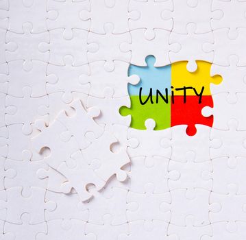 Puzzle pieces connected to each other with the word unity. Unity, synergy, integration or solidarity concept.