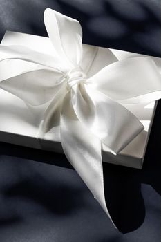 Anniversary celebration, shop sale promotion and luxe surprise concept - Luxury holiday white gift box with silk ribbon and bow on black background, luxe wedding or birthday present