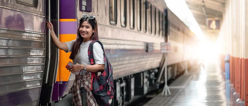 Portrait attraction asian woman boarding a train at train station for travel in summer. Travel concept.