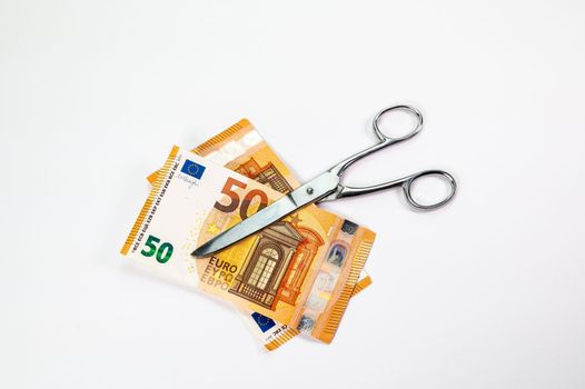cut 50 euro banknotes with scissors on white background