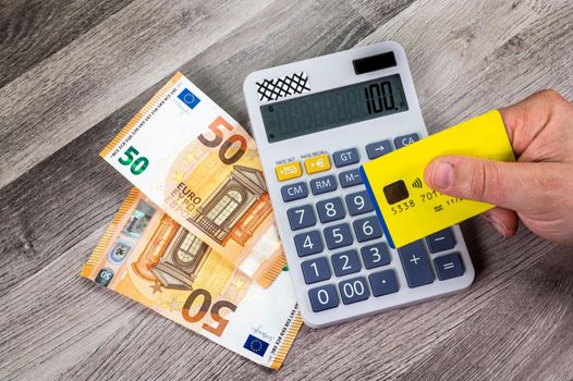 50 euro banknotes credit card with calculator close up on wooden table