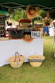 Elche, Alicante, Spain- June 20, 2021: Traditional craft hemp baskets, hats and raffia bags for sale at an ecological market in Elche, Alicante province, Spain.