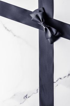 Holiday gift, decoration and sale promotion concept - Black silk ribbon and bow on marble background, flatlay