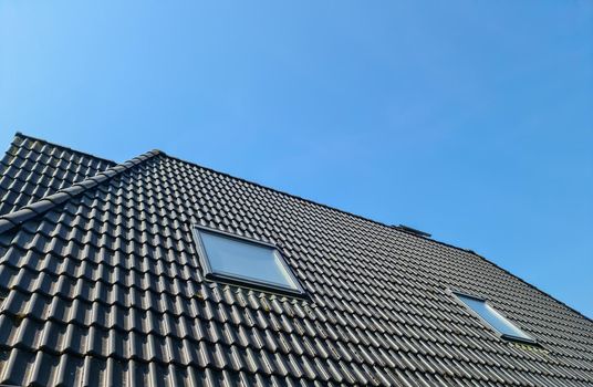 Open roof window in velux style with black roof tiles